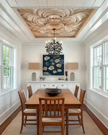 Stylish dining area featuring a unique wooden tray ceiling with intricate carvings, complemented by a modern chandelier, natural wood furniture, and bright white walls.