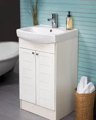 Small bathroom vanity with a white cabinet, built-in sink, and modern design, perfect for maximizing space in compact bathrooms. Set against a light blue shiplap wall with a wicker basket for towels.