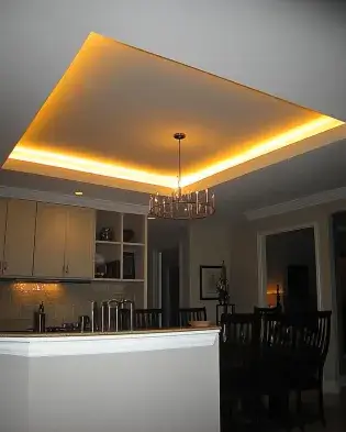 tray ceiling with hidden warm LED lighting and a modern chandelier, highlighting a cozy dining and kitchen area.