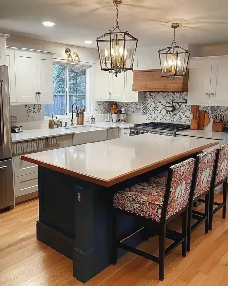 A stylish kitchen decor setup featuring white cabinets, a navy-blue island with a wooden countertop, patterned bar stools, and lantern pendant lights, creating a modern farmhouse aesthetic.