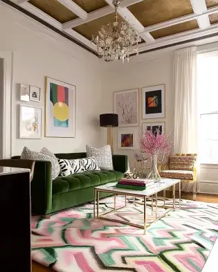 Stylish living room with a gold-accented tray ceiling, green velvet sofa, colorful artwork, and a vibrant geometric rug.